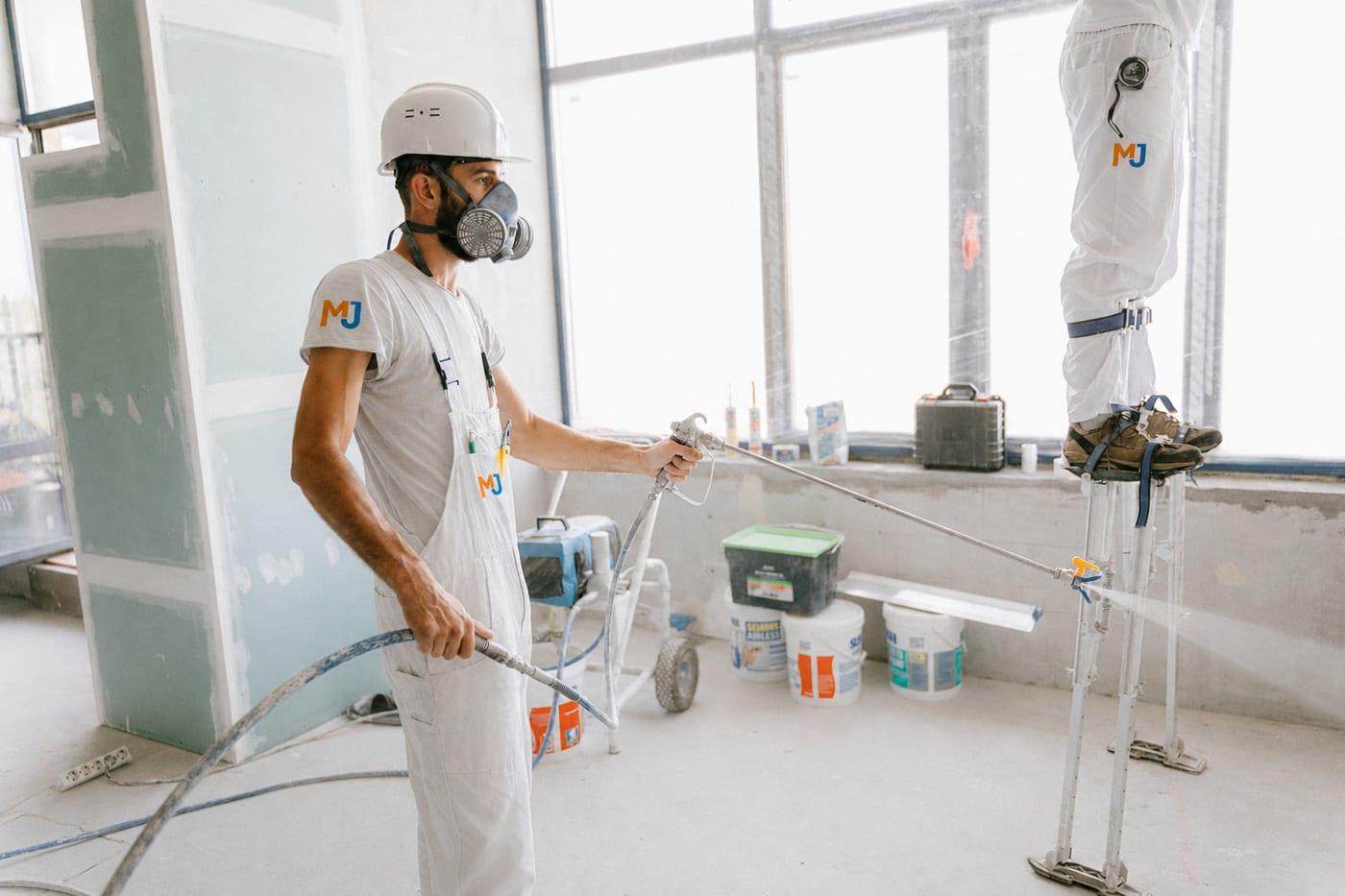 Técnico de MJ Serveis Integrals pintando con equipo de protección en una obra